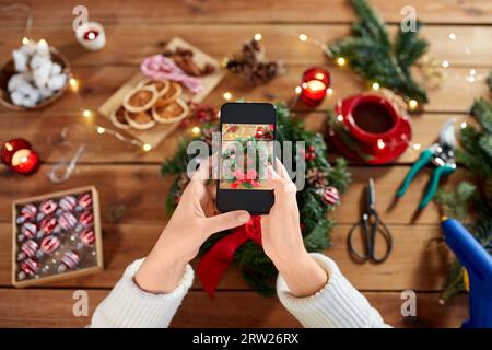 mani con telefono che fotografa la corona di natale Foto Stock