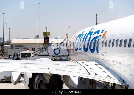 I passeggeri che salgono sulle scale aeree per gli aerei flydubai all'aeroporto di Dubai Foto Stock