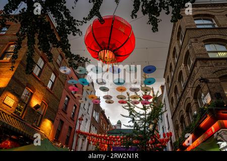 Londra, Regno Unito: Incrocio tra Gerard Street e Macclesfield Street a Chinatown di Londra. Lanterne rosse cinesi e ombrelloni colorati pendono sopra la strada. Foto Stock