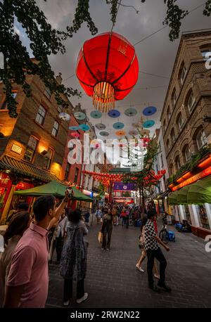 Londra, Regno Unito: Incrocio tra Gerard Street e Macclesfield Street a Chinatown di Londra. Lanterne rosse cinesi e ombrelloni colorati pendono sopra la strada. Foto Stock