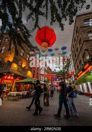 Londra, Regno Unito: Incrocio tra Gerard Street e Macclesfield Street a Chinatown di Londra. Lanterne rosse cinesi e ombrelloni colorati pendono sopra la strada. Foto Stock