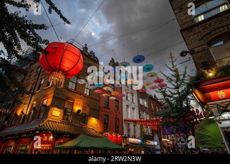 Londra, Regno Unito: Incrocio tra Gerard Street e Macclesfield Street a Chinatown di Londra. Lanterne rosse cinesi e ombrelloni colorati pendono sopra la strada. Foto Stock