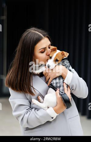 Felice, donna bacia con il suo cucciolo, il carino cucciolo Jack Russell Terrier per strada Foto Stock