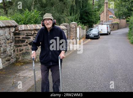 Uomo anziano che cammina ascoltando musica tramite cuffie Foto Stock