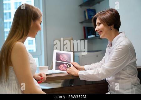 La mamma in attesa felice esamina le immagini ecografiche fetali con uno specialista Foto Stock