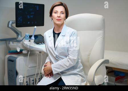 Donna in uniforme medica siede in comoda sedia da ufficio Foto Stock