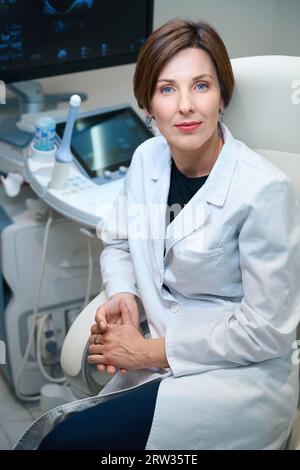 Una donna medico siede su una comoda sedia da ufficio sul posto di lavoro Foto Stock