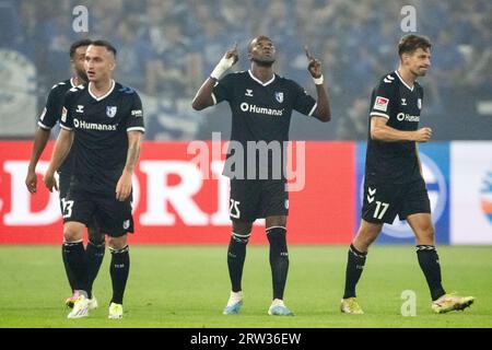 Gelsenkirchen, Germania. 16 settembre 2023. Calcio: 2° Bundesliga, FC Schalke 04 - 1. FC Magdeburg, il 6° giorno, Veltins Arena. Silas Gnaka (centro) di Magdeburgo celebra il suo gol per 1:0. Credito: Bernd Thissen/dpa - NOTA IMPORTANTE: conformemente ai requisiti della DFL Deutsche Fußball Liga e della DFB Deutscher Fußball-Bund, è vietato utilizzare o far utilizzare fotografie scattate nello stadio e/o della partita sotto forma di immagini di sequenza e/o serie di foto simili a video./dpa/Alamy Live News Foto Stock