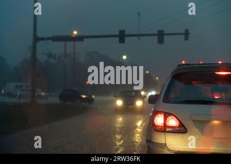 Trasporto notturno negli Stati Uniti. Auto che viaggiano in condizioni di pioggia sulla strada cittadina della Florida con traffico in movimento Foto Stock