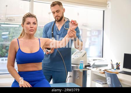 Fisioterapista che esegue una terapia extracorporea con onde d'urto Foto Stock