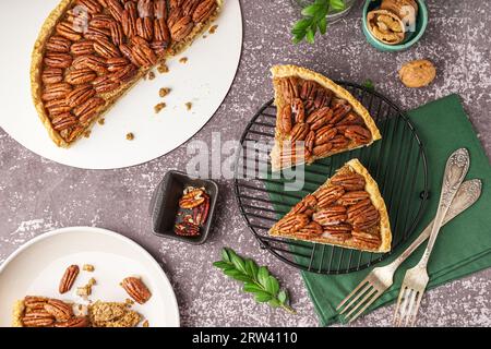 Griglia con pezzi di gustosa torta di noci pecan su sfondo grigio Foto Stock