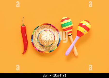 Peperoncino con cappello sombrero e maracas messicane per il giorno dell'indipendenza su sfondo arancione Foto Stock