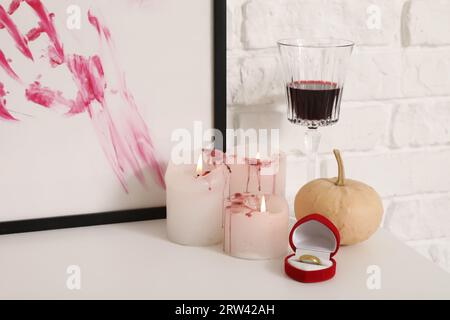 Zucca di Halloween con anello, drink e candele sul tavolo da spogliatoio in camera, primo piano Foto Stock