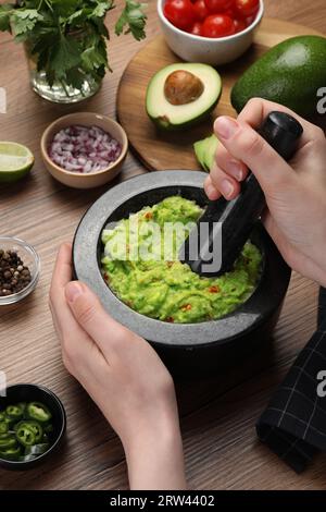 Donna che prepara guacamole delizioso al tavolo di legno, primo piano Foto Stock