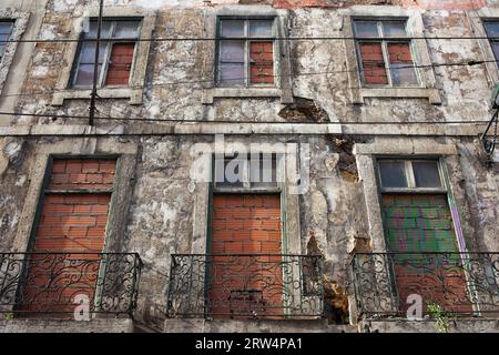 Facciata di un vecchio edificio di appartamenti a Lisbona, Portogallo, con finestre cieche coperte in mattoni Foto Stock