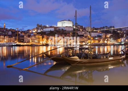 Città di Porto di notte in Portogallo. Rabelo barche tradizionali portoghesi da carico con botti di vino sul fiume Douro e lo skyline della città vecchia Foto Stock