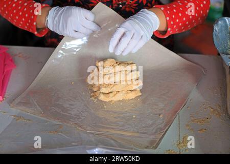 Le famiglie che lavorano stanno confezionando caramelle croccanti di arachidi in un laboratorio di famiglia. Foto Stock