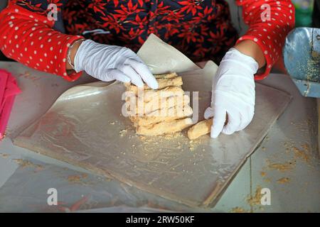 Le famiglie che lavorano stanno confezionando caramelle croccanti di arachidi in un laboratorio di famiglia. Foto Stock
