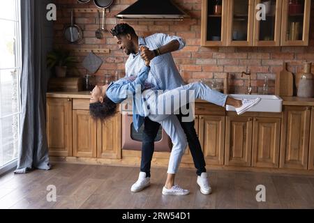 Eccitata coppia afroamericana che balla in cucina, godendo di un appuntamento romantico Foto Stock