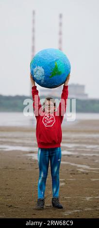 Chloe Coghlan, 12 anni, con un modello di pianeta Terra, si unisce alla società civile e ai gruppi di azione per il clima che manifestano a Sandymount Strand a Dublino, invitando il governo a intraprendere azioni urgenti per eliminare gradualmente i combustibili fossili che distruggono il clima. La loro dimostrazione fa parte di un'ondata globale di manifestazioni e marce che si stanno svolgendo in tutto il mondo, chiedendo una rapida ed equa eliminazione dei combustibili fossili. Data foto: Domenica 17 settembre 2023. Foto Stock