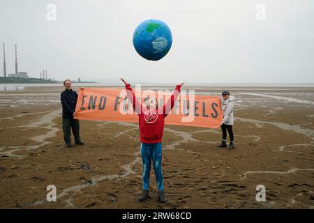 Chloe Coghlan, 12 anni, con un modello di pianeta Terra, si unisce alla società civile e ai gruppi di azione per il clima che manifestano a Sandymount Strand a Dublino, invitando il governo a intraprendere azioni urgenti per eliminare gradualmente i combustibili fossili che distruggono il clima. La loro dimostrazione fa parte di un'ondata globale di manifestazioni e marce che si stanno svolgendo in tutto il mondo, chiedendo una rapida ed equa eliminazione dei combustibili fossili. Data foto: Domenica 17 settembre 2023. Foto Stock