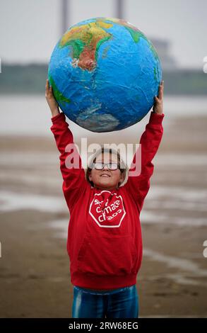 Chloe Coghlan, 12 anni, con un modello di pianeta Terra, si unisce alla società civile e ai gruppi di azione per il clima che manifestano a Sandymount Strand a Dublino, invitando il governo a intraprendere azioni urgenti per eliminare gradualmente i combustibili fossili che distruggono il clima. La loro dimostrazione fa parte di un'ondata globale di manifestazioni e marce che si stanno svolgendo in tutto il mondo, chiedendo una rapida ed equa eliminazione dei combustibili fossili. Data foto: Domenica 17 settembre 2023. Foto Stock