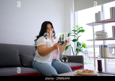 La donna Plus size sta mangiando la ciambella. Concetto di assistenza sanitaria e stile di vita. Foto Stock