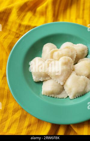 Ravioli a forma di cuore giacciono su un piatto verde. Cibo preparato, pasto romantico, sorpresa per la persona amata Foto Stock