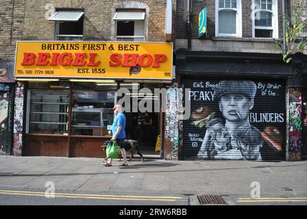 Immagine di Brick Lane con il famoso negozio di bagel fondato nel 1855 e alcune opere di Street art di Peaky Blinders sulle persiane accanto. Foto Stock