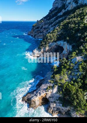 Una splendida spiaggia con una maestosa scogliera situata lungo la costa dell'oceano in Sardegna, Italia. Foto Stock