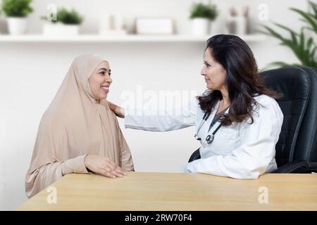 La giovane donna musulmana indiana che indossa hijab si consulta sul suo problema con la ginecologa donna dottore in clinica moderna. Foto Stock