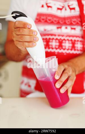 lo chef prepara il frullato a casa versando il frullato nel bicchiere dopo la cottura. Foto Stock