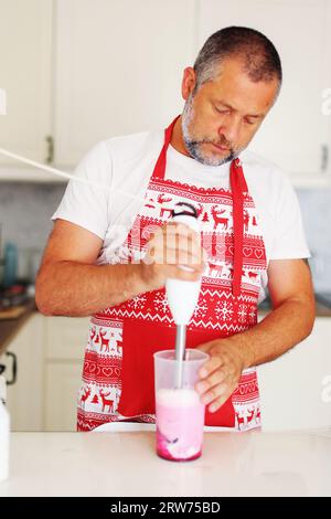 lo chef prepara il frullato a casa versando il frullato nel bicchiere dopo la cottura. Foto Stock