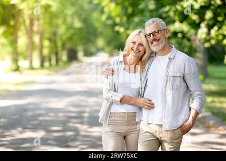 Bellissimi sposi maturi che si abbracciano all'aperto mentre camminano nel parco estivo Foto Stock
