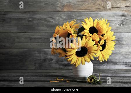 Bouquet di girasoli in vaso su sfondo ligneo con spazio per le copie. Fiori autunnali. Stagione autunnale. Foto Stock