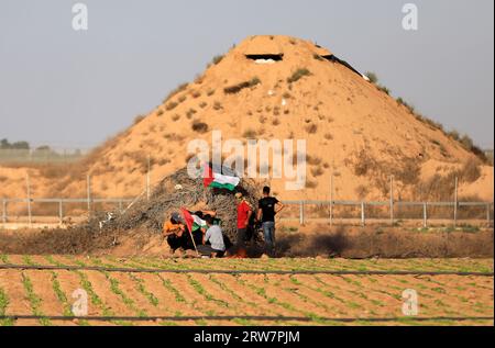 Un manifestante palestinese lancia una tanica di gas lacrimogeni sparata dalle forze di sicurezza israeliane lungo la recinzione che separa Gaza e Israele, a est della città di Khan Yunis, nella Striscia di Gaza meridionale. Foto Stock