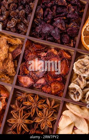 Variazione di frutta secca fragola, mela, ciliegia, banana, pesca, prugna e anice stellato in una scatola su uno sfondo di cemento scuro Foto Stock