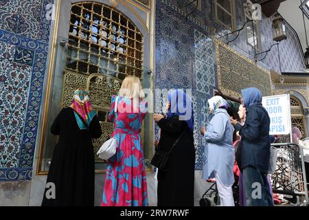 Donne musulmane che pregano di fronte al muro piastrellato della tomba del sultano di Eyüp presso la moschea del sultano di Eyüp a Istanbul, Turchia Foto Stock