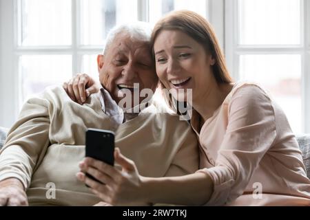 Padre anziano felice e figlia adulta fanno selfie al cellulare Foto Stock