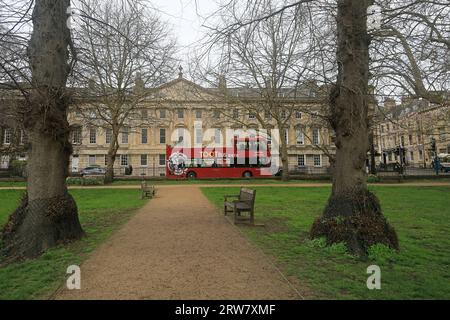Vista di Queen's Square e di un autobus turistico rosso scoperto (Toot Bus) dal piccolo parco, città di Bath, Inghilterra. Settembre 2023 Foto Stock