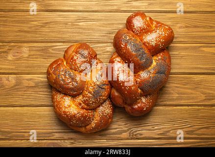 Due pane Challah appena sfornato ricoperto di papavero e semi di sesamo, vista dall'alto su uno sfondo rustico di legno, tradizionale cucina ebraica festosa Foto Stock