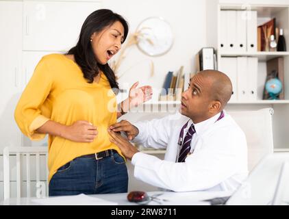 Il medico esamina il paziente con dolore acuto Foto Stock