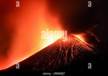 Etna - Esplosione di lava tensa in dettaglio dal cratere durante l'eruzione vista di notte con silhouette del cratere in controluce 13 agosto 2023 Foto Stock