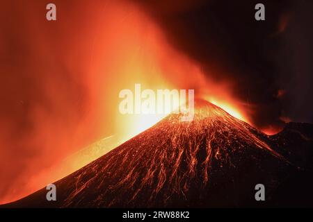 Etna - Esplosione di lava tensa in dettaglio dal cratere durante l'eruzione vista di notte con silhouette del cratere in controluce 13 agosto 2023 Foto Stock