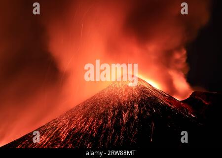 Etna - Esplosione di lava tensa in dettaglio dal cratere durante l'eruzione vista di notte con silhouette del cratere in controluce 13 agosto 2023 Foto Stock