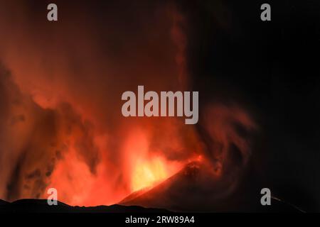 Etna durante una suggestiva eruzione notturna dal cratere del vulcano con volti e forme immaginarie create dalle emissioni di fumo. Agosto 2023 Foto Stock