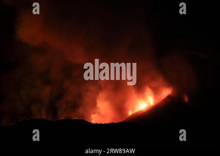 Etna durante una suggestiva eruzione notturna dal cratere del vulcano con volti e forme immaginarie create dalle emissioni di fumo. Agosto 2023 Foto Stock