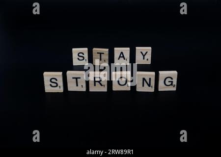 Lake Elsinore, CA, USA - 17 settembre 2023: Piastrelle scricchiolate isolate su sfondo nero che descrivono "Stay strong". Foto Stock