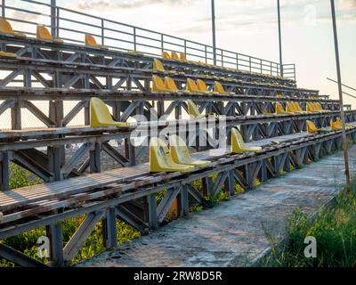 Vecchie sedie di plastica rotte allo stadio. Stand abbandonato allo stadio. Concetto di devastazione. Non ci sono fan. Foto Stock