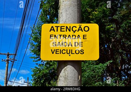 Cartello di avvertimento in portoghese che informa "attenzione, ingresso e uscita dei veicoli", Ribeirao Preto, San Paolo, Brasile Foto Stock